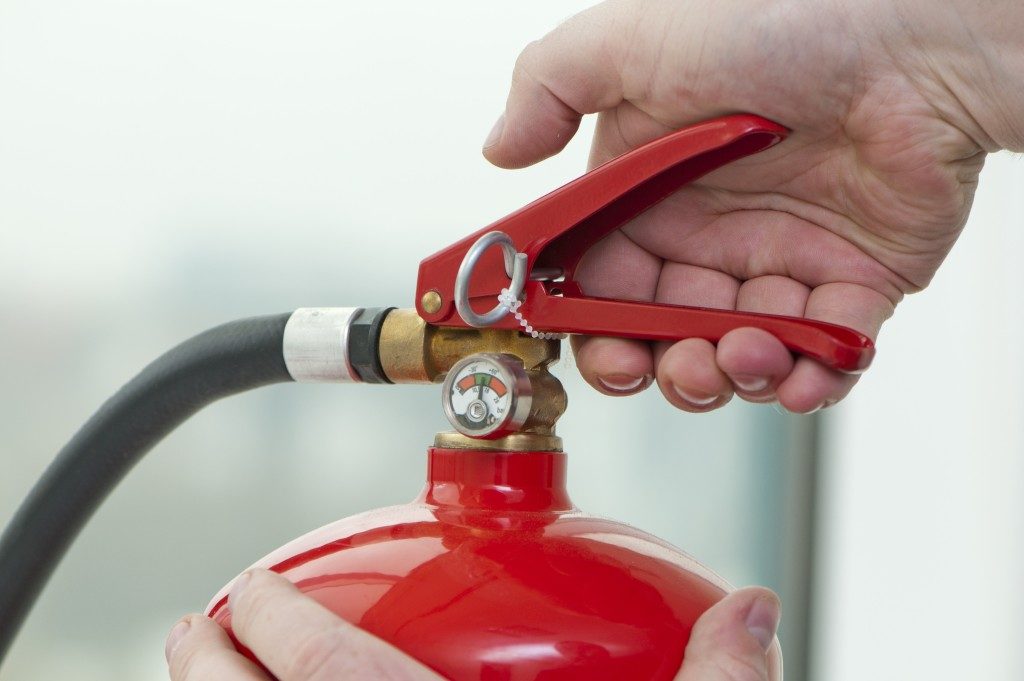 Hand pressing the trigger on a fire extinguisher