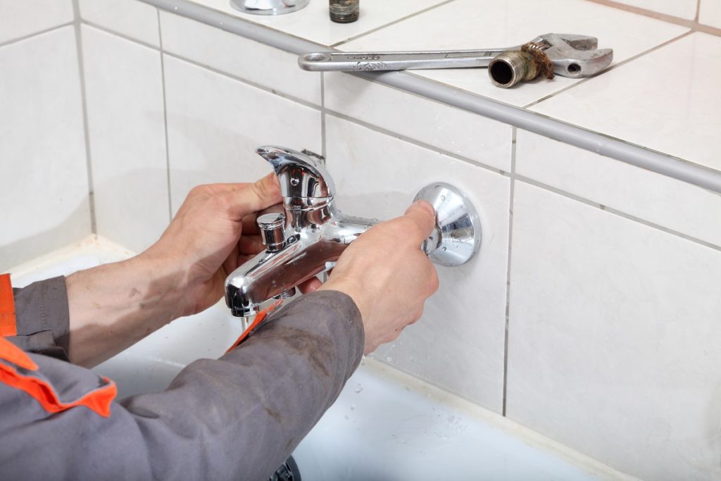 Plumber fixing water tap with spanner