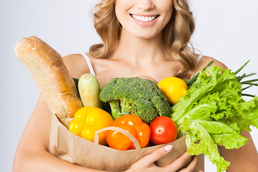 holding grocery shopping bag with healthy vegetarian raw food