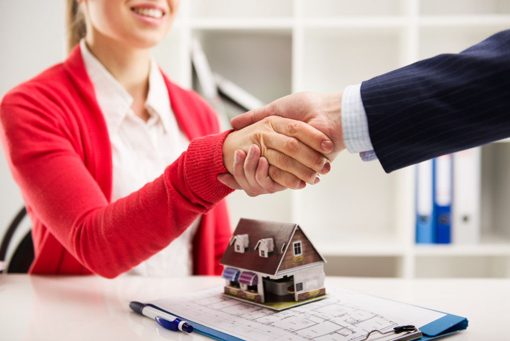 woman about to buy a property shaking hands with a real estate agent